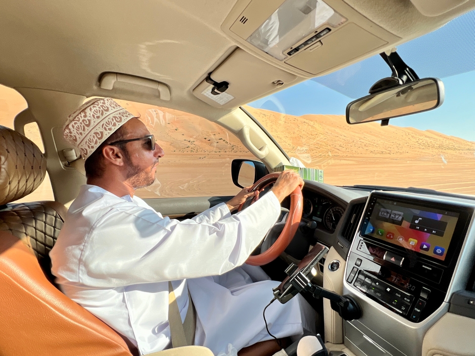 Homme conduisant un véhicule dans le désert avec une vue à travers la fenêtre.