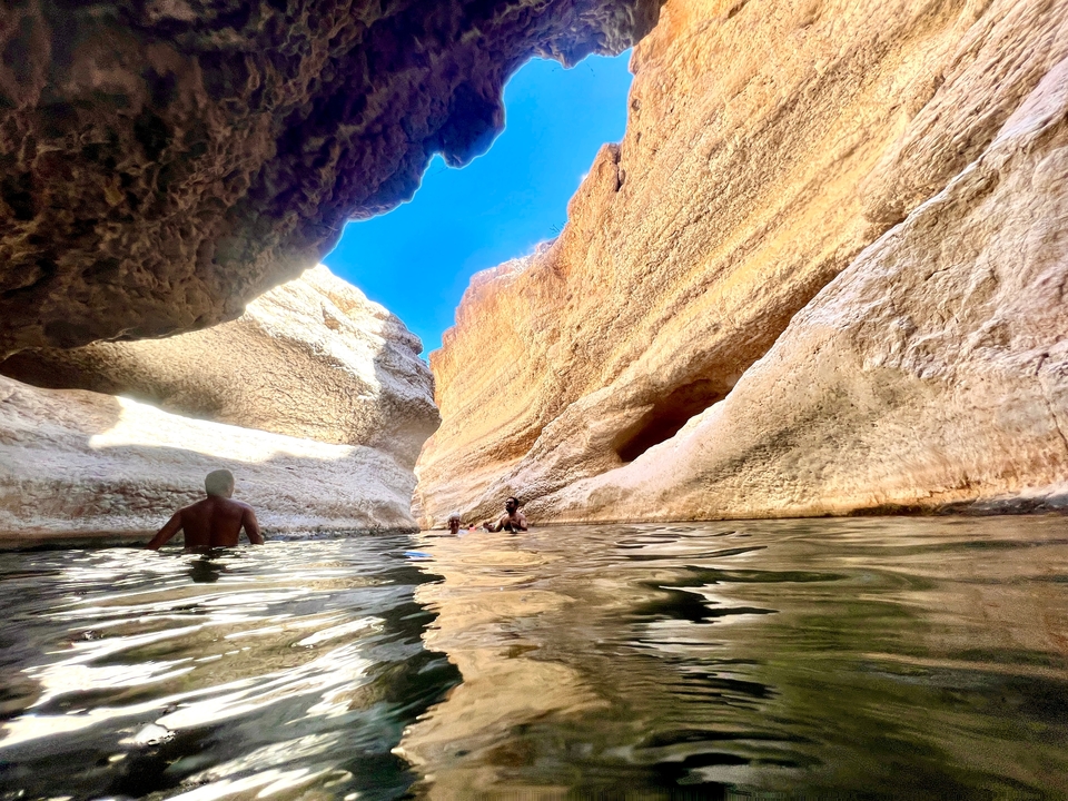 Des gens qui nagent dans le plan d'eau naturel encadré par des falaises rocheuses.