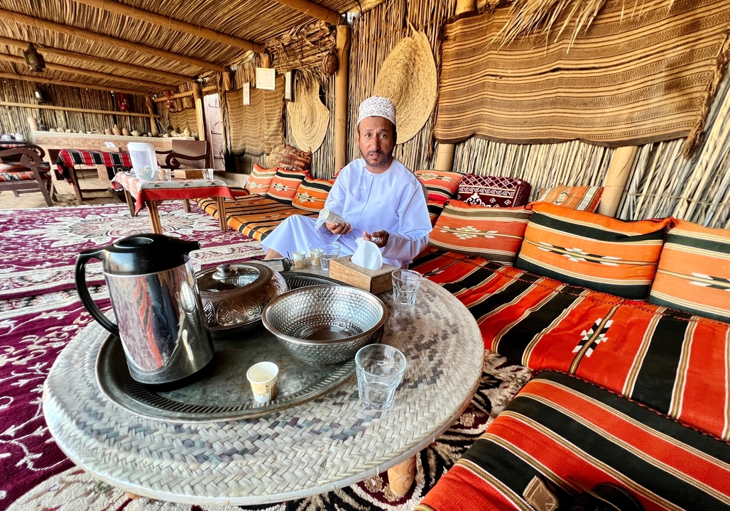 Personne dégustant du thé dans une tente décorée de manière traditionnelle.