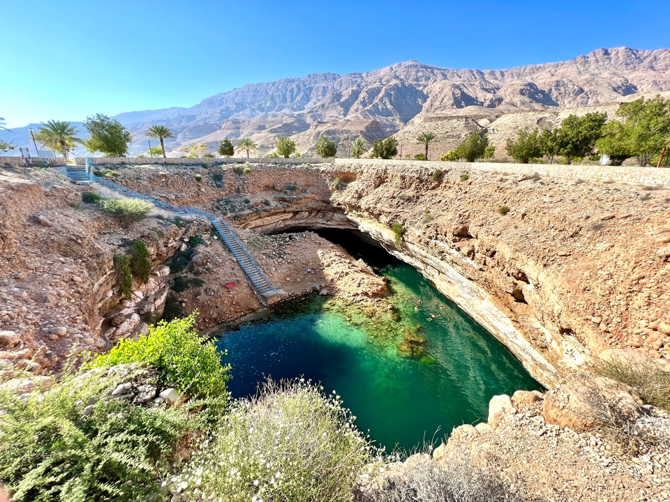 Gouffre de Bimmah entouré de terrain rocheux et d'eau.