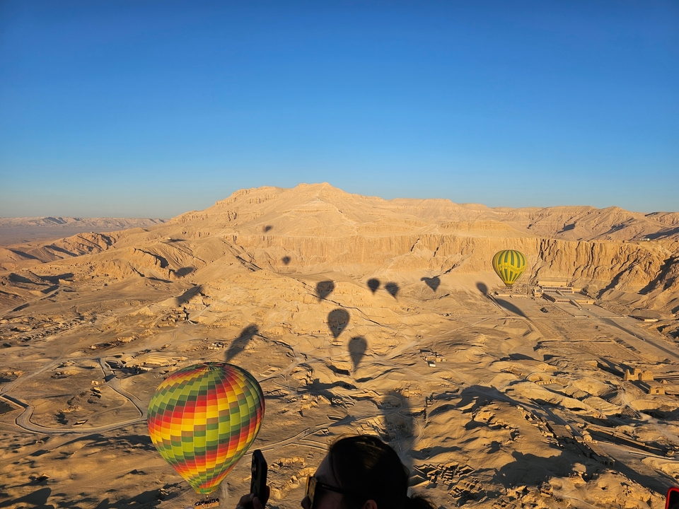 Hot air balloons over a desert landscape during sunrise.