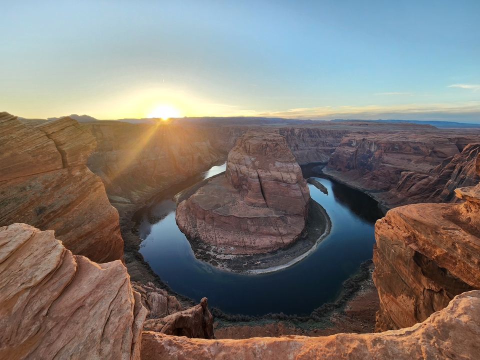 Une vue panoramique de Horseshoe Bend avec le fleuve Colorado qui serpente et le soleil qui se couche.