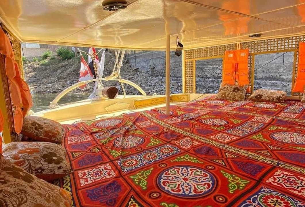 Coussins et couvertures colorés à l'intérieur d'un bateau donnant sur une berge.