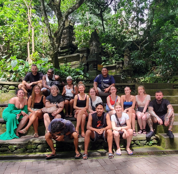 Group of travelers posing on stone steps surrounded by greenery.