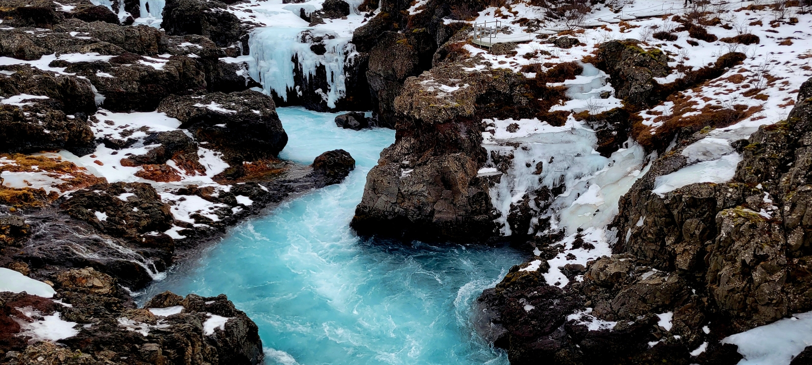 Frozen river with blue water and icy rocks.