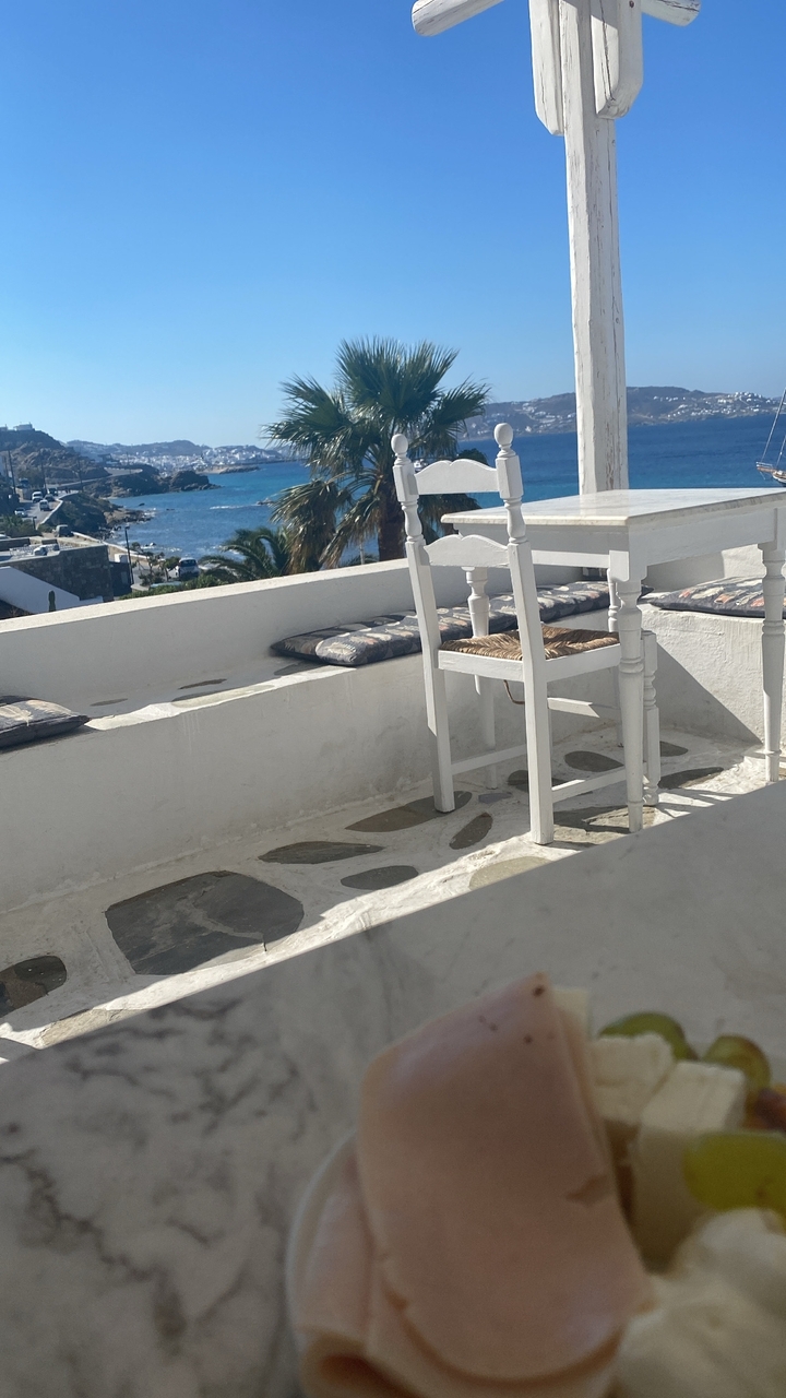 Zone de restauration extérieure avec table et vue sur mer.