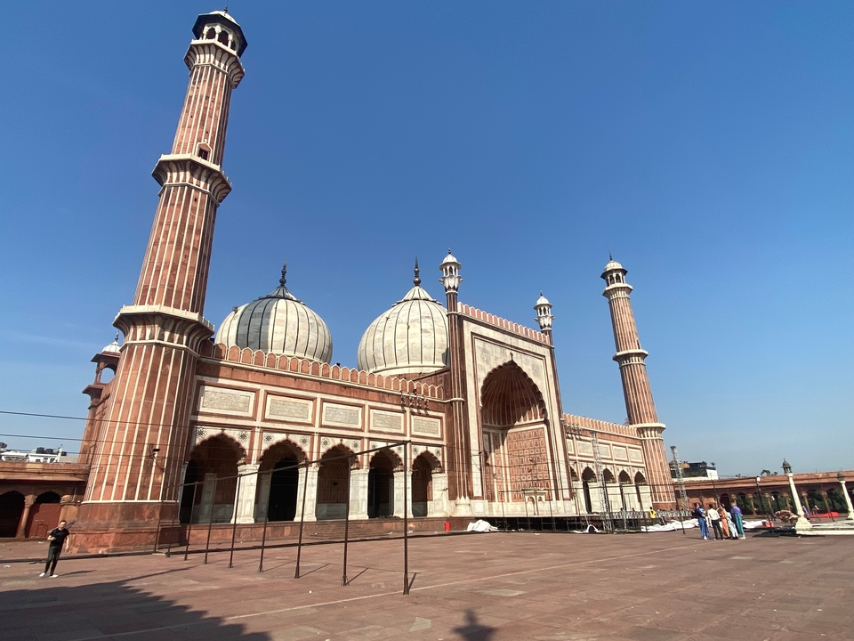 Grande mosquée avec une cour et de hauts minarets sous un ciel bleu.