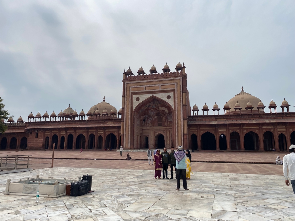 Cour historique de mosquée avec des gens qui déambulent.