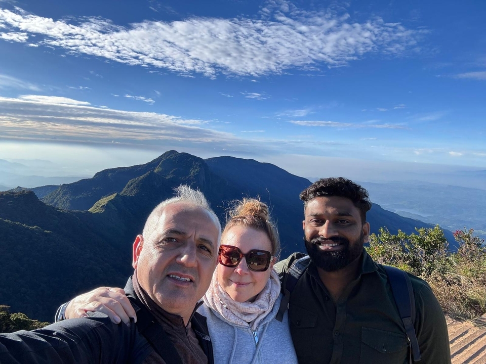 Groupe de personnes posant avec des montagnes en arrière-plan.