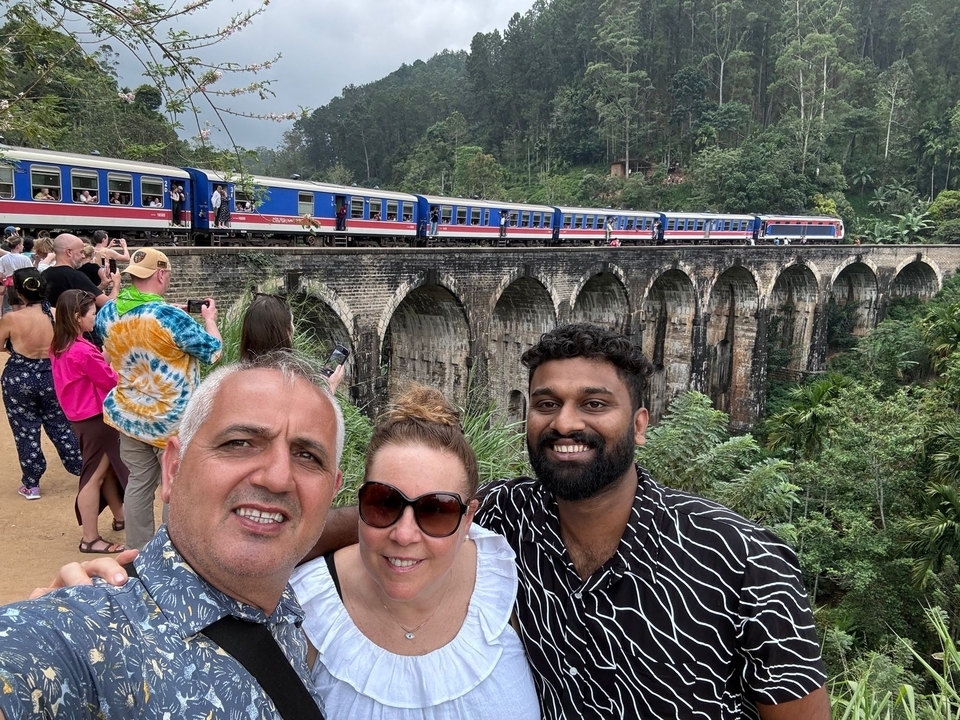 Des gens qui prennent des photos près d'un train sur un pont célèbre.