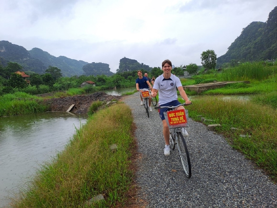 Des personnes font du vélo sur un sentier de gravier à travers un paysage verdoyant.