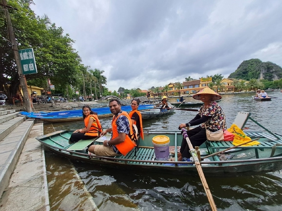 Groupe de personnes dans des bateaux sur une rivière près d'une ville.