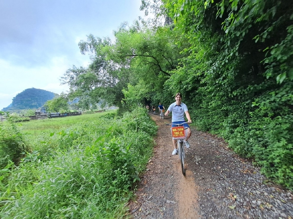 Personne faisant du vélo le long d'un sentier boisé verdoyant.