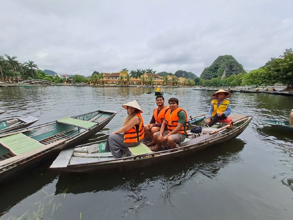 Famille sur un bateau avec des chapeaux traditionnels sur un lac.