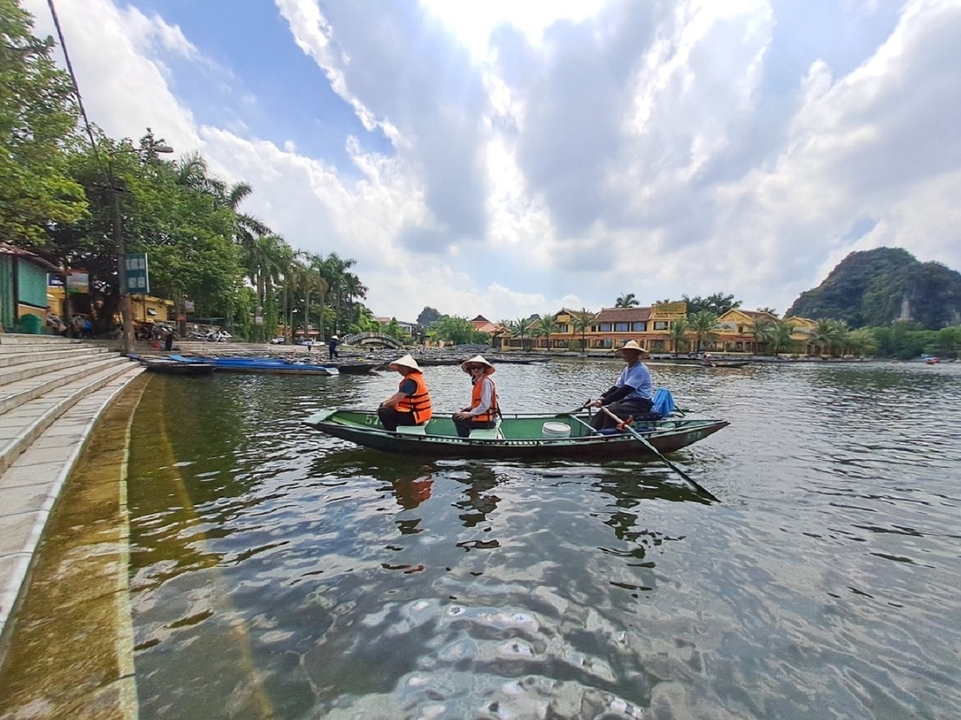 Deux personnes dans un bateau avec des chapeaux vietnamiens traditionnels.