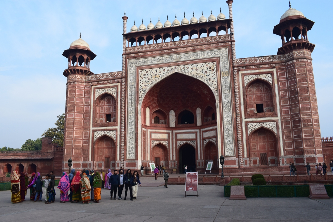 La porte d'entrée du complexe du Taj Mahal avec des gens qui marchent.