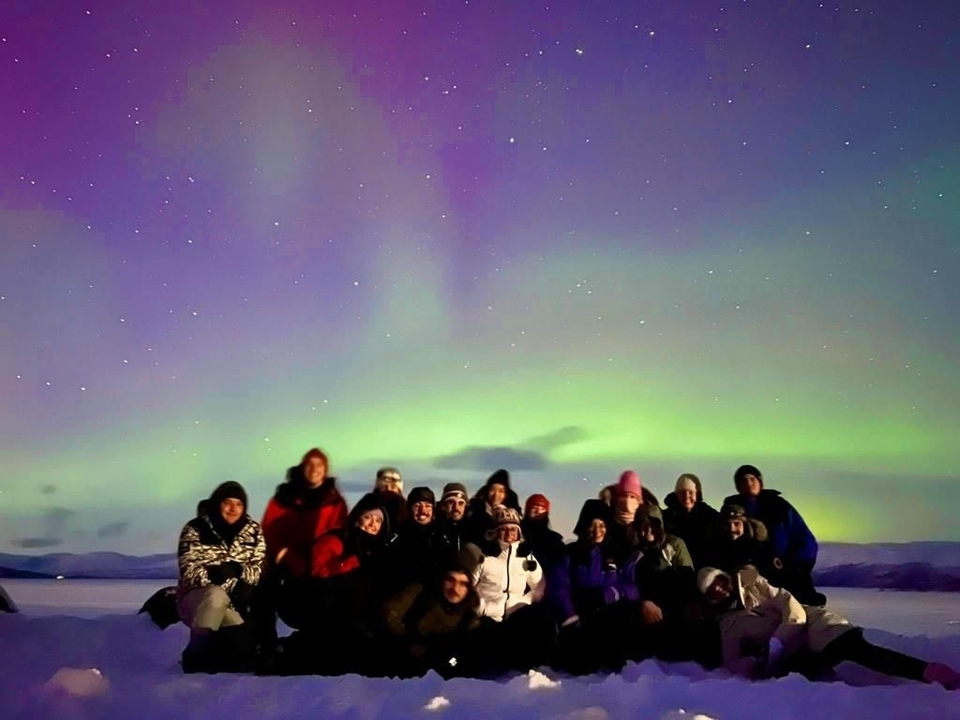 Un groupe assis sous les aurores boréales.