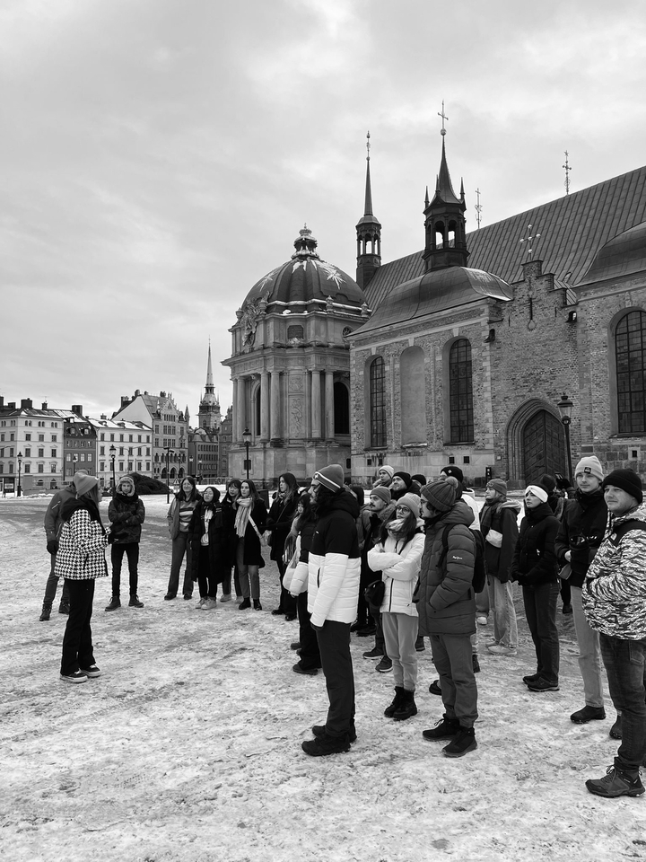 Un groupe de personnes écoutant un guide sur une place de la ville.