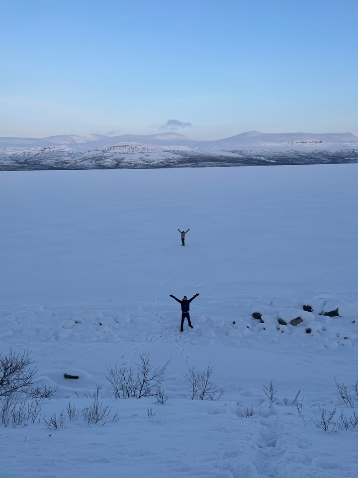 Deux personnes se tiennent debout dans un vaste champ enneigé.
