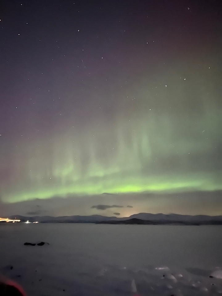 Aurore boréale dans un ciel nuageux.
