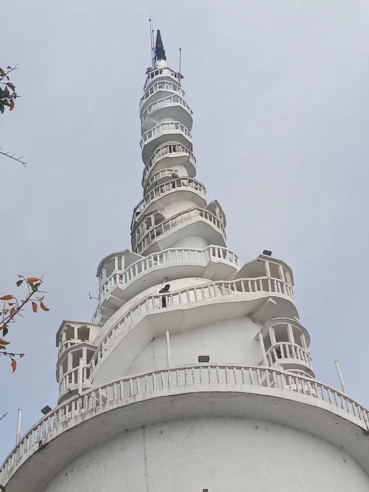 Haute tour blanche avec plusieurs balcons contre un ciel clair.
