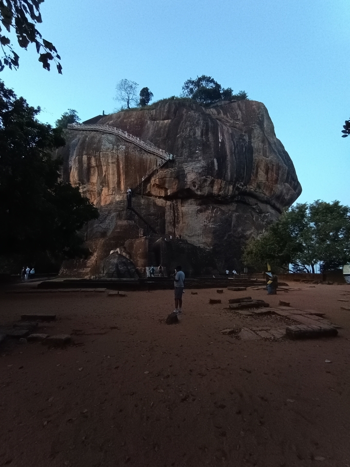 Rocher de Sigiriya avec escaliers et personnes qui grimpent.