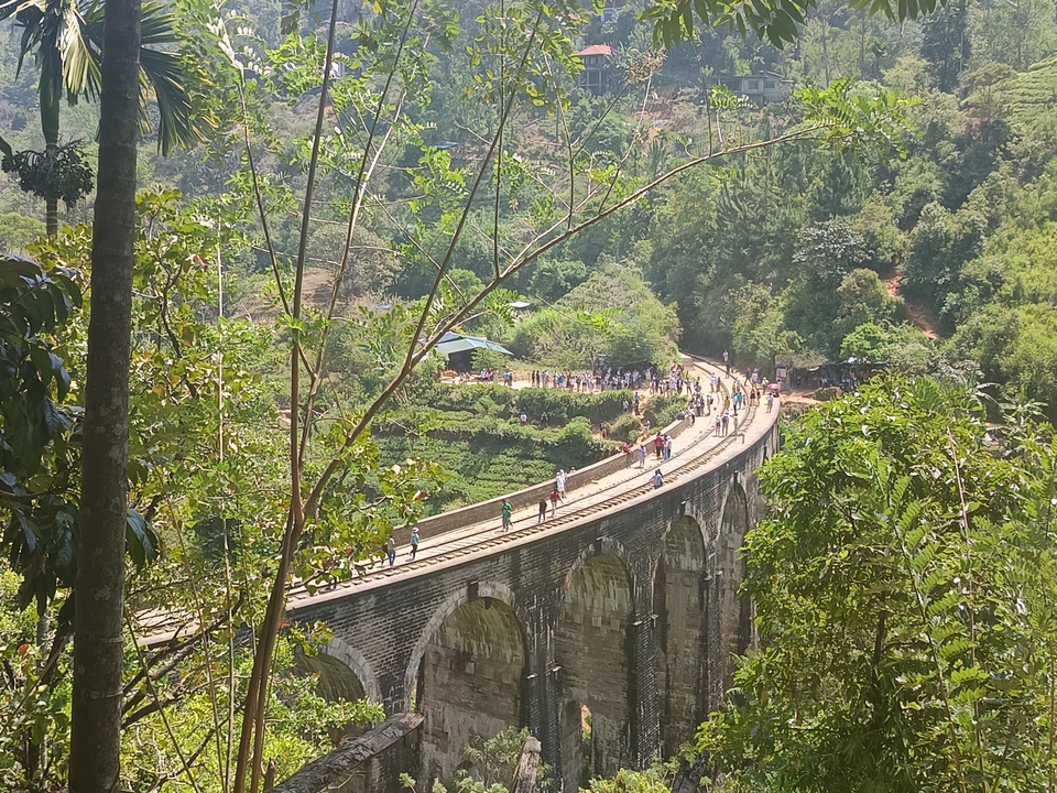 Pont à Neuf Arches avec des personnes qui marchent dessus, entouré d'un paysage verdoyant.