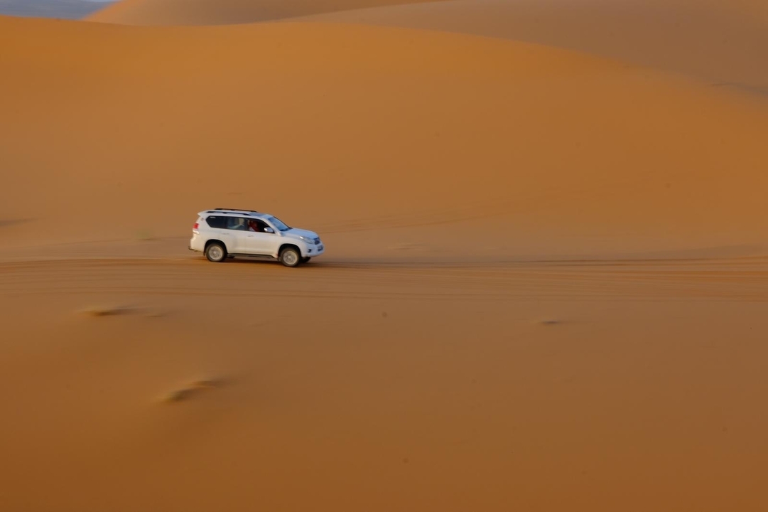 SUV roulant rapidement à travers les dunes de sable.