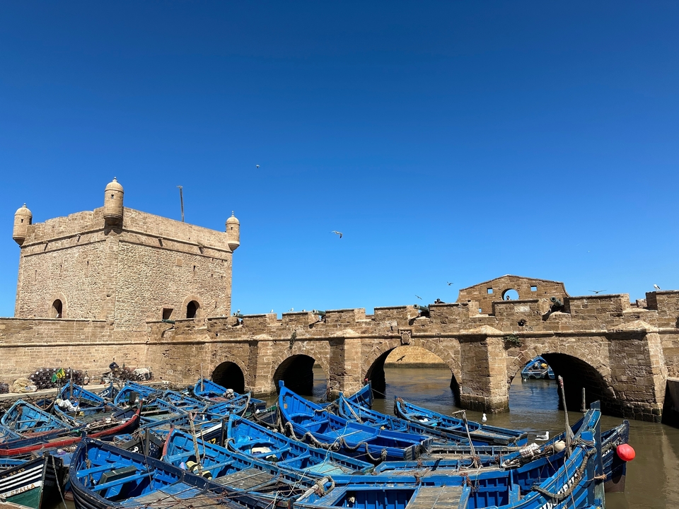 Forteresse de pierre avec une tour entourée d'eau et de bateaux bleus.