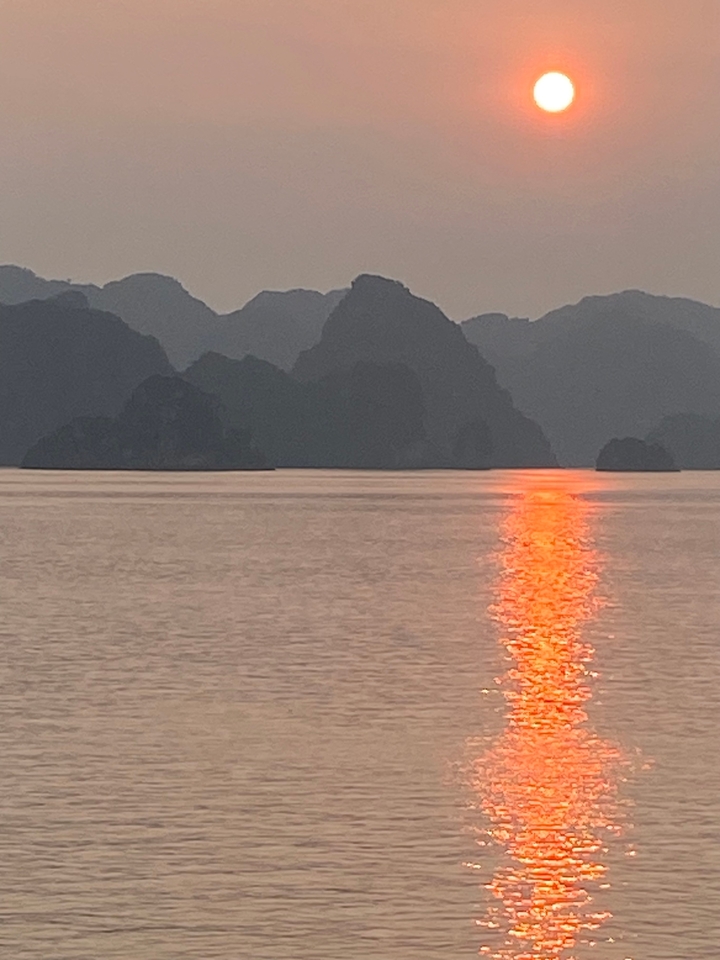 Coucher de soleil sur un lac avec des montagnes en silhouette.