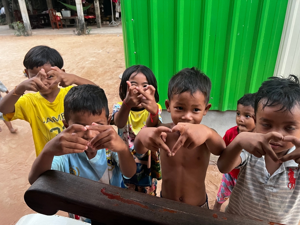 Groupe d'enfants souriants et faisant des gestes de la main.