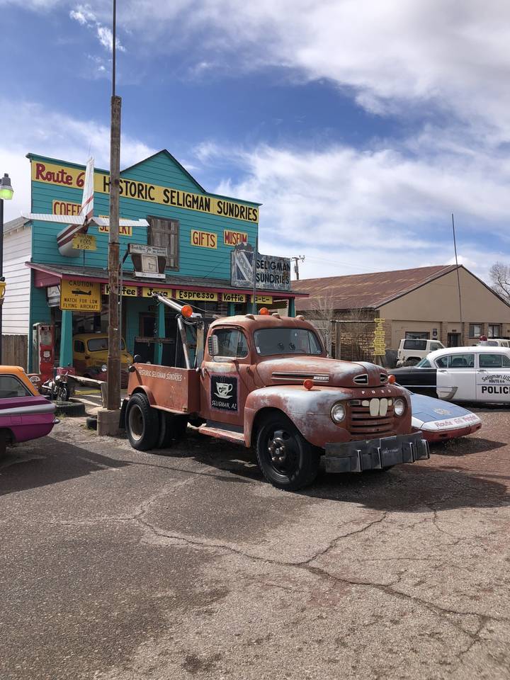 Voiture de collection garée devant des magasins historiques dans une petite ville.