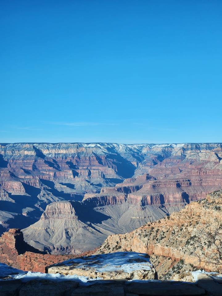 Paysage de canyon saupoudré de neige avec un ciel bleu dégagé.
