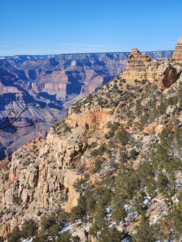 Vue d'un canyon avec des falaises rocheuses et un ciel bleu dégagé.