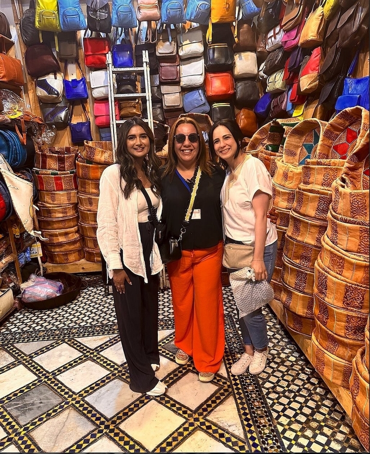 Trois femmes posant dans un marché avec des articles en cuir.