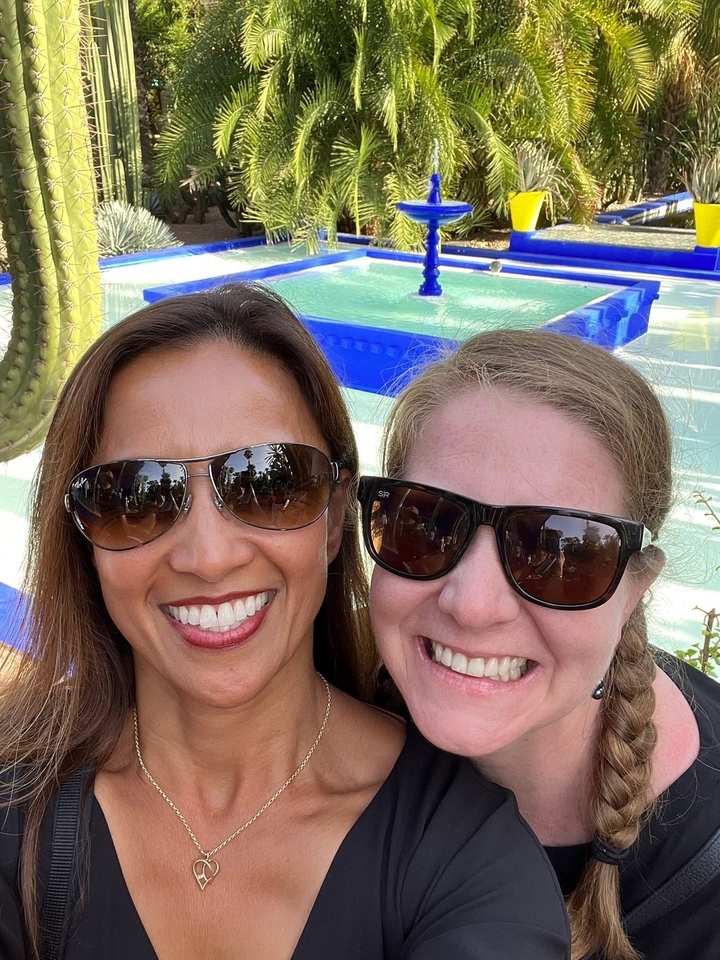 Deux femmes souriantes avec des lunettes de soleil dans un jardin.