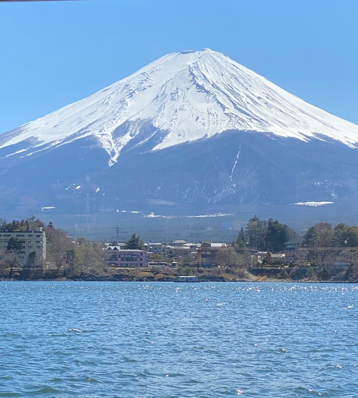 Le mont Fuji qui domine une ville au bord d'un lac.
