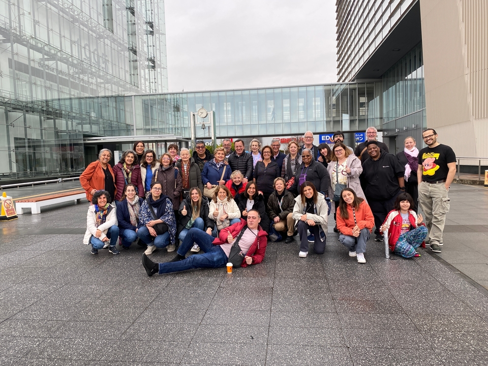 Grand groupe de personnes souriantes devant un bâtiment moderne.