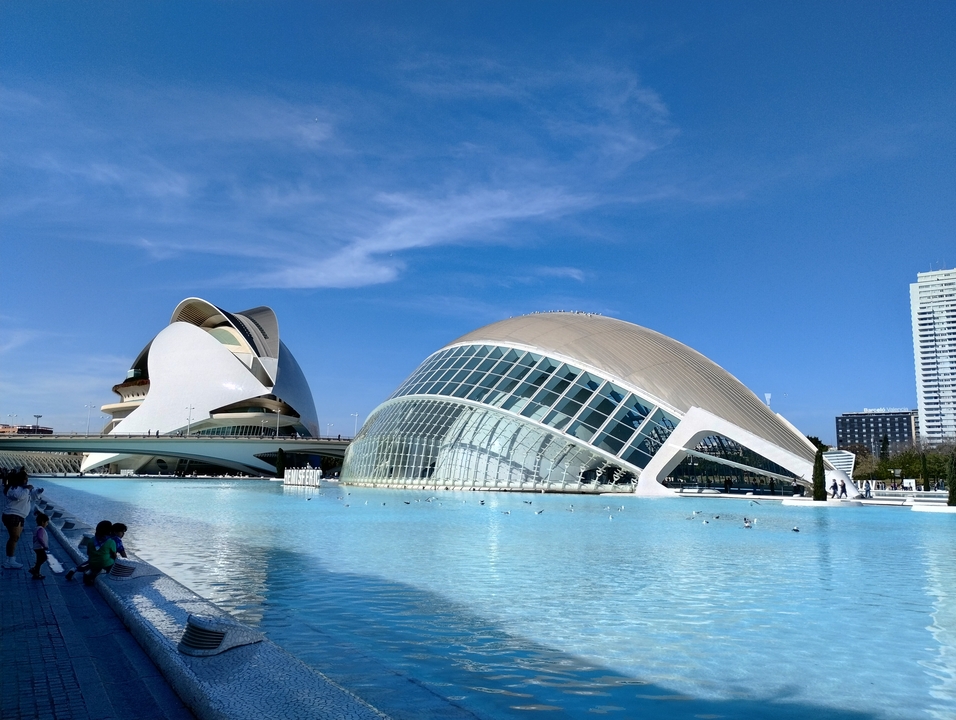 Bâtiments modernes avec des reflets dans l'eau sous un ciel bleu dégagé.