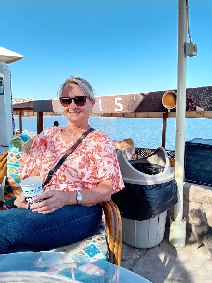 Femme tenant une tasse sur un bateau avec vue sur l'eau.
