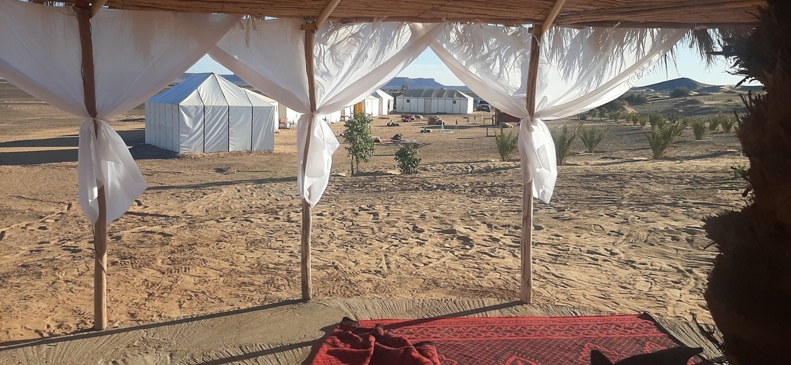 Vue depuis une tente donnant sur un campement dans le désert.