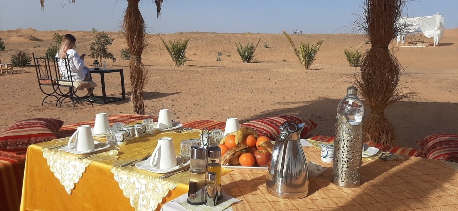 Petit-déjeuner en plein air dans le désert avec une personne en arrière-plan.