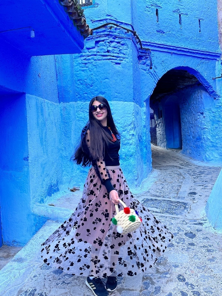 Femme marchant dans une ruelle bleue étroite.