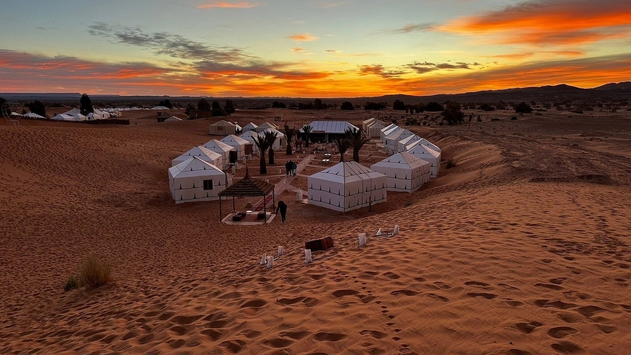 Campement dans le désert avec des tentes au coucher du soleil.