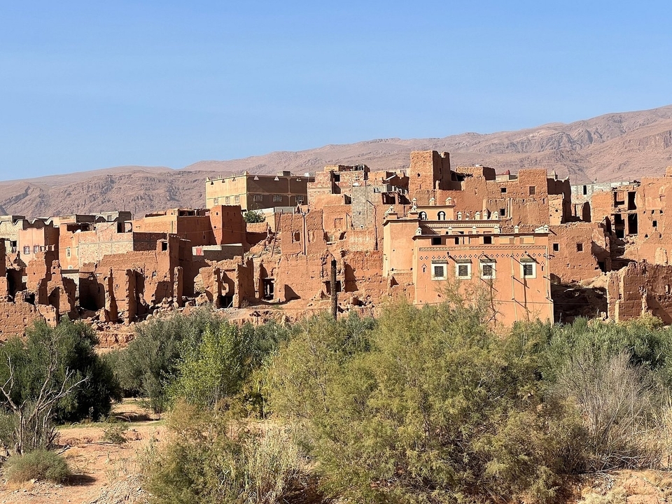 Kasbahs en briques de terre crue entourées de végétation dans un paysage désertique.