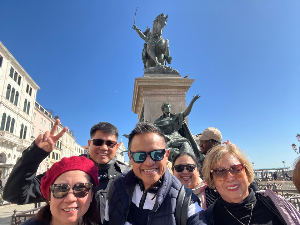 Groupe de personnes posant près d'une statue sur une place de la ville.