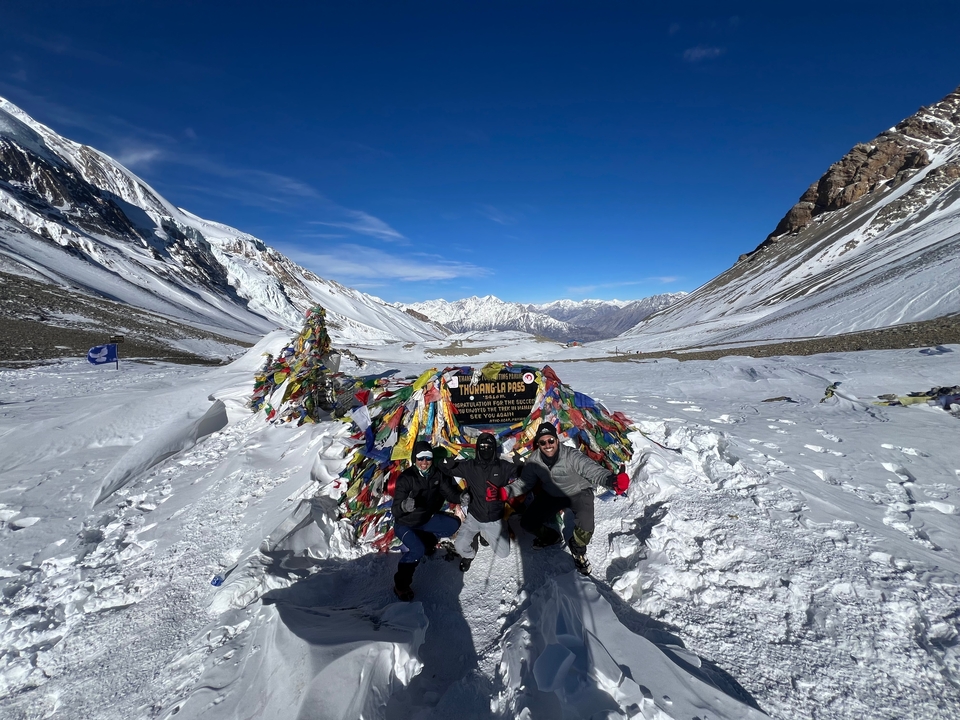 Groupe posant sur un paysage enneigé avec des drapeaux de prières