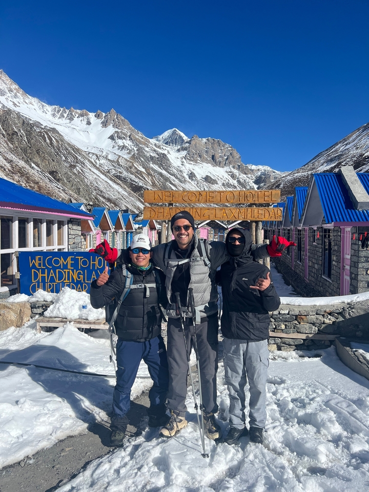 Trois personnes posant devant un hôtel dans une région montagneuse