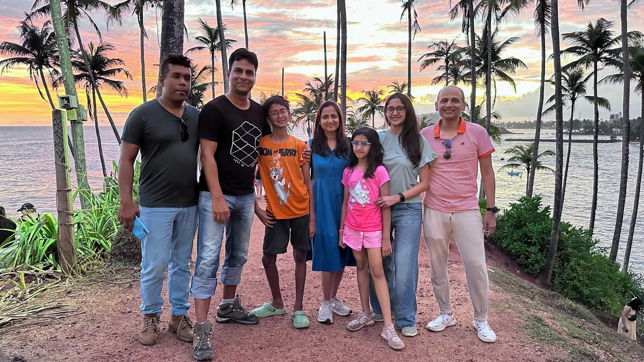 Une famille posant devant un coucher de soleil avec des palmiers.