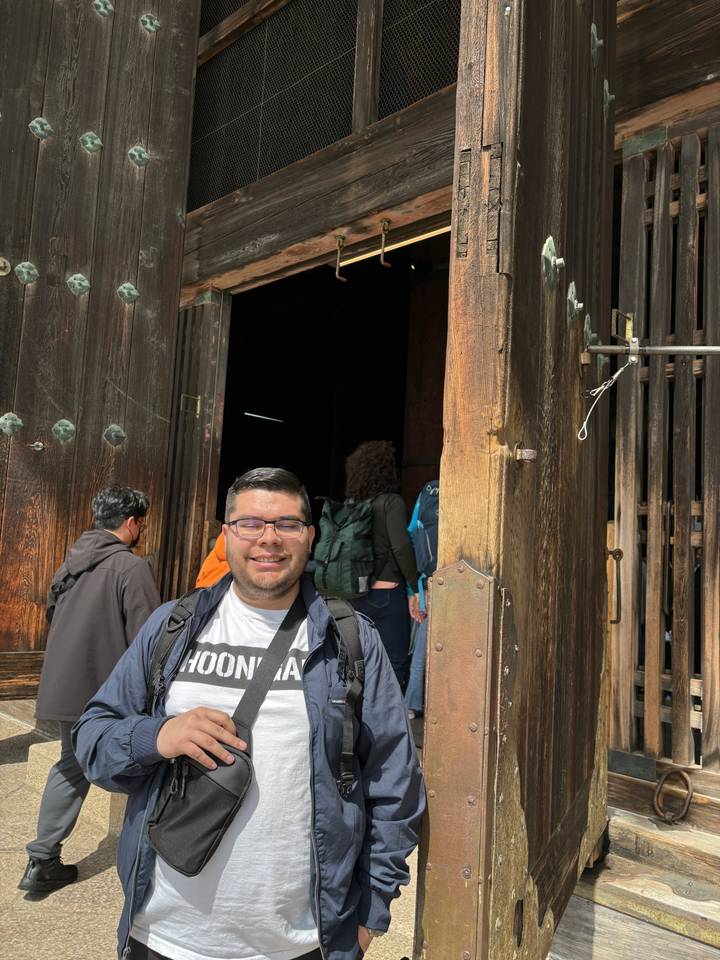 Personne debout dans l'embrasure d'une porte en bois avec la lumière qui éclaire son visage.